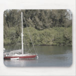 Veleiro vermelho em árvores do rio atrás mousepad