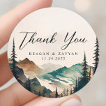 Adesivo Casamento De Pinheiros Das Montanhas Watercolor Ob<br><div class="desc">Conte sua gratidão com a beleza tranquila do Casamento de Pinheiros das Montanhas Watercolor, Obrigado Clássico Round Sticker. Este adesivo, impresso em material durável, apresenta uma cena serena de aquarela de montanhas e uma floresta de pinheiros. Uma mensagem sincera de "Obrigado", escrita na tipografia moderna, aprecia o centro do autocolante....</div>