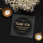 Adesivo Obrigado Arte Moderna Deco Negra e Dourado Casamen<br><div class="desc">O Clássico Arte Moderna Deco Preto e Dourado Casamento é a maneira perfeita de dizer obrigado com estilo. Apresenta um fundo preto elegante e sotaques geométricos de ouro elegantes. Ideal para selar envelopes ou adicionar um toque pessoal aos seus favores, este adesivo captura a sofisticação do design de Arte moderna....</div>