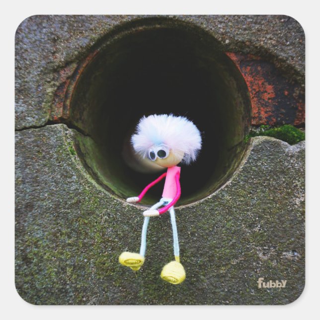 Adesivo Quadrado Fubby poppetje dat in een muur zit.  (Frente)