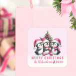 Adesivo Quadrado Pink Christmas Custom Family Name (Nome personaliz<br><div class="desc">Crie adesivos de Natal feminino personalizados para selagens de envelopes ou favores com um design cor-de-rosa que diz "Feliz Natal" e contém pinguins alegres perto de uma árvore de Natal trocando enfeites. O modelo facilita a digitação do nome da família e do ano.</div>