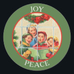 Adesivo Vintage Image Christmas Carolers<br><div class="desc">Uma imagem de vintage de um grupo de mulheres cantando canções de Natal é a característica deste adesivo colorido. A cena é vista através de um painel de janelas, com um pino vermelho de arco atrás dos carolers. A imagem é enquadrada em vermelho, e colocada em uma borda verde Feriado...</div>