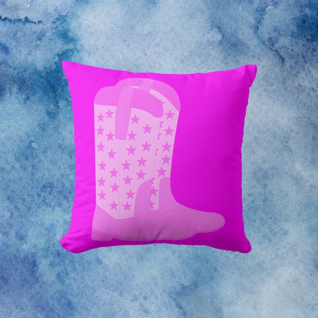 Almofada Botas de vaqueiro com estrelas cor-de-rosa (A throw pillow with a pair of pink cowboy boots with stars on a pink background.)