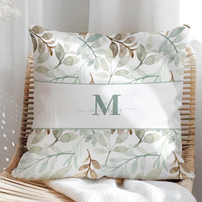 Almofada Folhas de aquarela com nome personalizado e inicia (Watercolor leaves with Custom Name and Initial Throw Pillow in a sunny rattan armchair.)