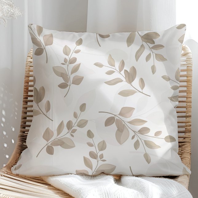 Almofada Folhas de bege e de aquarela branca (Beige and White Watercolor Leaves Throw Pillow in a sunny rattan armchair.)