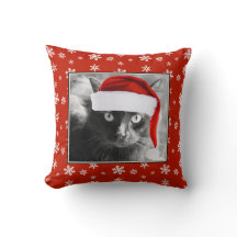 Gato do Natal no travesseiro vermelho com flocos