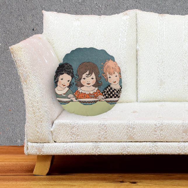 Almofada Redonda Vintage Meninas Comendo Sopa Três Irmãs (Three little girls sitting together eating soup on tan and blue round decorative pillow.)