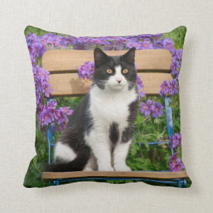 Almofada Tuxedo gato sentado numa cadeira de jardim com flo
