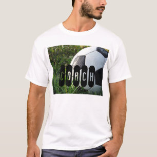 Bola de futebol preto e branco no t-shirt da grama