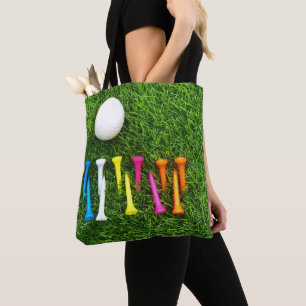 Bolsa Tote camisetas de golfe estão na grama verde.