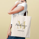 Bolsa Tote Dama de honra com Monograma Preto e Dourado Elegan<br><div class="desc">Glamour atemporal encontra elegância clássica com esta bolsa tote apresentando uma inicial de monograma dourada sobreposta a um nome personalizado em letra cursiva sofisticada preta e o papel da dama de honra abaixo. Um souvenir de monograma luxuoso com um brilho dourado quente que eleva qualquer celebração de casamento. Nome, inicial...</div>