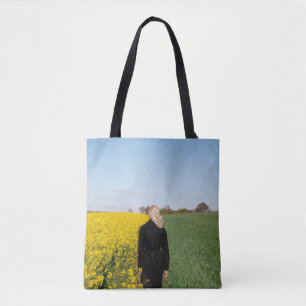 Bolsa Tote Mulher em casaco preto em pé sobre grama verde 