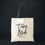 Bolsa Tote Noiva da Equipe de Letra de Mão Negra Personalizad<br><div class="desc">BRIDE TEAM personalizável para o saco. Saco de tota moderno e clássico com um script preto de inscrição manual "Team Bride". Personalize adicionando o nome do receptor,  a hashtag do casamento ou outros detalhes. Perfeito como presente para sua festa de casamento ou festa noiva.</div>