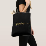 Bolsa Tote Nome do Monograma Personalizado Preto Dourado Simp<br><div class="desc">Menina Feminina, Mínima Simples, Preto Limpo E Nome Monograma Dourado, Script Personalizado De Tote Bag. Este design com seu primeiro nome em um estilo bonito, escrito à mão, estilo swash tail, tipografia de assinatura (ou caligrafia) em fundo preto e ouro. presente feminina excelente para aniversário, casamento, Natal, doce festa de...</div>