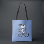 Bolsa Tote Peanuts | Snoopy & Woodstock Bicycle<br><div class="desc">Pedal into style and classic charm with this adorable cream canvas tote bag, featuring Snoopy and Woodstock on a bicycle! This fun tote showcases a delightful line-art illustration of Snoopy, wearing sunglasses, happily riding a vintage-style blue bicycle with Woodstock perched safely behind him. The dashed lines behind the back wheel...</div>