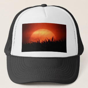 Boné Sol vermelho atrás da grama preta
