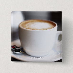 Bóton Quadrado 5.08cm latte na mesa, fim-acima da chávena de café
