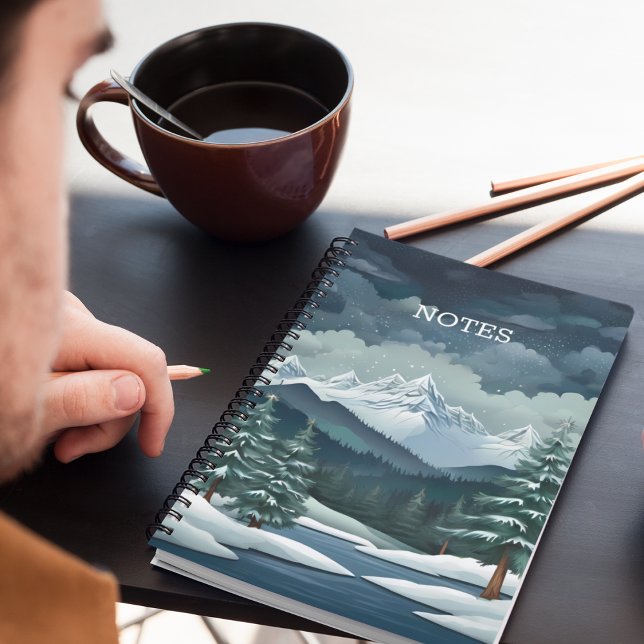 Caderno Espiral Cena da Floresta de Inverno (A snowy forest mountain scene notebook on a desk with pencils and coffee.)