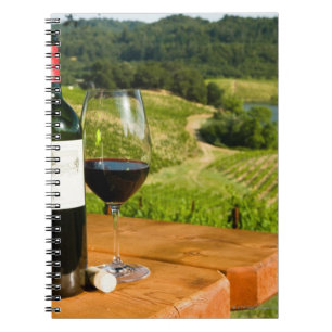 Caderno Espiral Garrafa do vinho tinto e do vidro na mesa