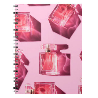 Caderno Espiral Garrafas de perfume, fundo rosa, flatlay