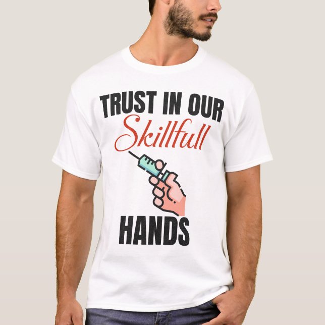 Camiseta Confiança Engraçada Em Nossas Mãos Hábil Flebotomi (Frente)
