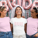Camiseta de Noiva | Futuro Nome da Sra. Personaliz<br><div class="desc">Esta camiseta moderna e personalizada para noivas é o look perfeito para qualquer noiva! Com o texto "BRIDE" em rosa suave e elegante, combinado com o texto manuscrito "futuro(a) Sra. [Seu Nome]" abaixo, essa camiseta é ideal para chás de noiva, despedidas de solteira, preparativos para o casamento e viagens de...</div>