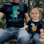 Camiseta Dia de os pais do Novo papai legal Dino Daddysauru<br><div class="desc">Design de texto personalizável com um legal T-rex teal moderno em óculos de sol segurando coração,  presente para Dia de os pais,  Aniversário ou Natal. Encontre uma camisa de dinossauro de criança na minha coleção "pai e eu designs".</div>