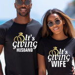 Camiseta É Dando Casamento de Lua de mel ao Recem casados M<br><div class="desc">Branca preta e camisa dourada "Está dando ao marido" para um noivo. Excelente para uma festa de solteira,  lua de mel,  aniversário ou visto diário para um cônjuge orgulhoso. Personalize-o com o seu sobrenome ou altere as cores.</div>