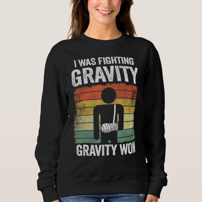 Camiseta Eu Estava Lutando Com Gravidade Ganhei Mão Quebrad (Frente)
