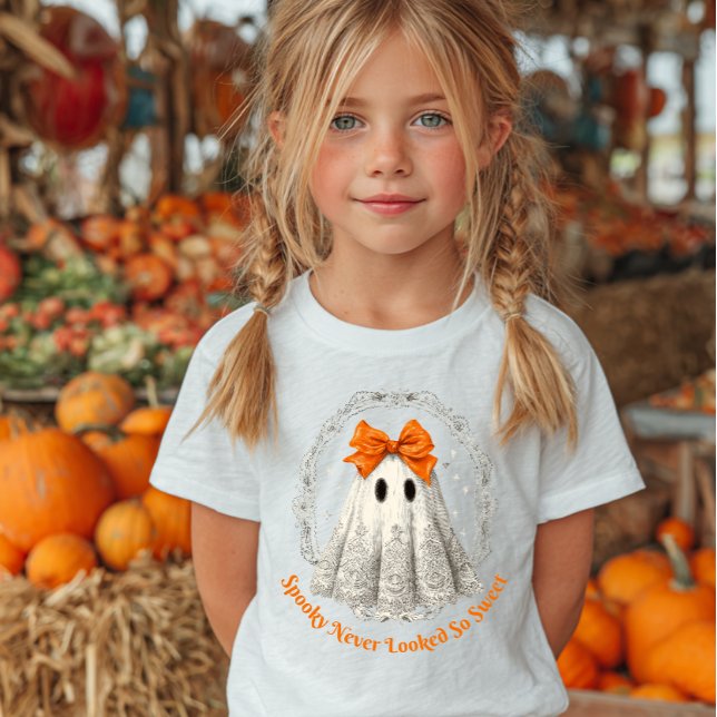 Camiseta Lace Ghost with Bow in Wreath and Stars (Young girl with blonde pigtails wearing a Halloween-themed T-shirt featuring a cute ghost.)