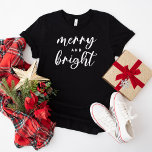 Camiseta Natal das mulheres negras felizes e brilhantes<br><div class="desc">Uma festa de Natal festiva para mulheres com tipografia moderna de escrita em minúsculas com "Feliz e Brilho" dizendo. O texto branco e o estilo de camisa preta podem ser modificados.</div>