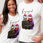 Camiseta Natal de Casais Personalizados de Script Engajado<br><div class="desc">Camisas de natal personalizadas. Esta design de aquarela tem uma ilustração de tendência de um casal vestindo chapéus de Santa. "Engaged" é escrito à mão em um roteiro moderno e o modelo está pronto para você adicionar seus nomes e o ano ou outro texto personalizado.</div>