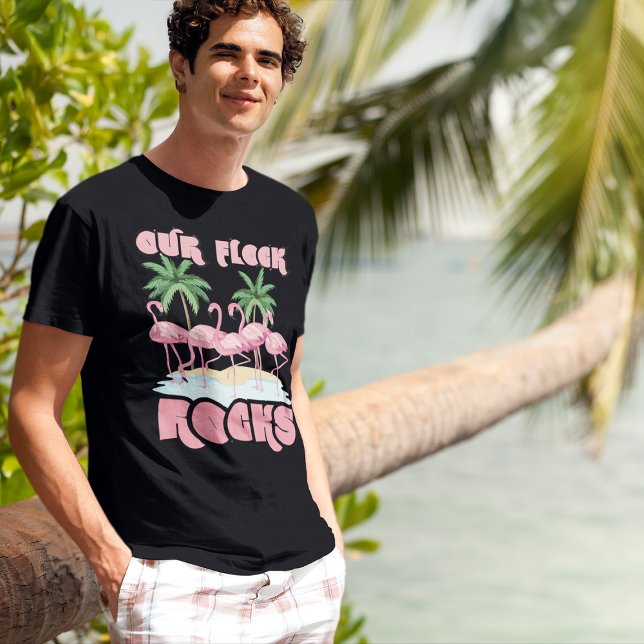 Camiseta Nosso Grupo Familiar Flamingos Correspondentes (young man in tropical beach setting wearing pink flamingo Our Flock Rocks family reunion t-shirt)