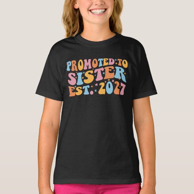 Camiseta Promovida a Irmã Est 2027 Irmã Mais Velha (Frente)