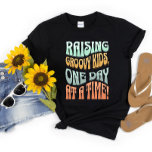 Camiseta Raising Groovy Kids Mãe A Vida Retro Engraçada<br><div class="desc">Mostre suas habilidades de parentalidade com esta na moda "Raising Groovy Kids, One Day at a Time!" retro t-shirt design. Perfeito para qualquer mãe que queira adicionar algum talento de vintage ao seu guarda-roupa enquanto mostra orgulhosamente o seu estilo de parentalidade, esta t-shirt torna-se certamente um favorito. Compre agora o...</div>