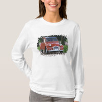 Um velho Citroen 2CV vermelho com uma mulher sorri