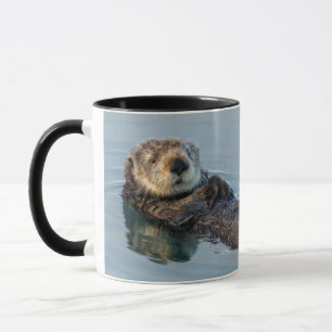 Caneca Lutra marinha flutuando de costas no oceano