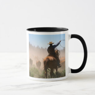 Caneca Um vaqueiro trabalhando com o rebanho em uma boiad