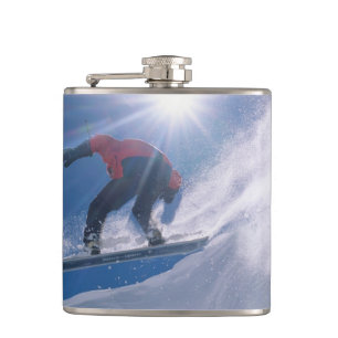 Cantil Homem saltando de uma grande cornija de snowboard