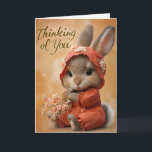 Cartão Autumn Blossom Baby Bunny Thinking of You Card<br><div class="desc">This beautifully tender “Thinking of You” card features a baby bunny dressed in an orange autumn romper and bonnet, holding a bouquet of soft peach blossoms. With her shy, heartwarming expression and warm amber backdrop, this card is perfect for offering comfort, support, or a sweet reminder that someone is in...</div>