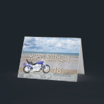 Cartão de aniversário de 18 anos com bicicleta mot<br><div class="desc">Um motociclo azul em pé numa praia com nuvens lisas no céu. Feliz Aniversário escrito em rock refletido na água que está na areia.</div>