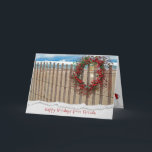 Cartão De Festividades Grinalda da praia da baga do Natal na cerca<br><div class="desc">grinalda da baga na cerca da praia com dólar da estrela do mar e de areia com fundo da água.
Beira rasgada da borda adicionada.</div>