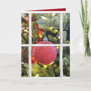 Cartão De Festividades red Christmas ornament in snowy window