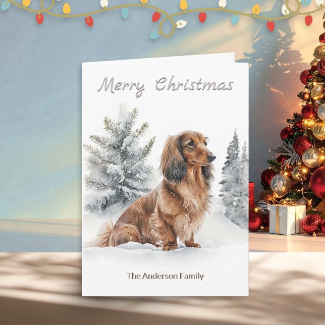 Cartão De Festividades Salsicha de Dachshund de Cabelo Longo Cão Feliz Na (A Christmas card with illustration of a long-haired dachshund "sausage dog" with pine trees in snow)