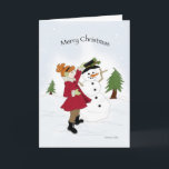 Cartão De Festividades Snowman e Little Girl<br><div class="desc">Menina num casaco vermelho vestindo um boneco de neve na neve</div>