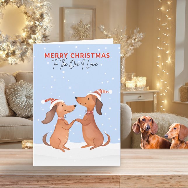 Cartão De Festividades Um Eu Adoro Feliz Natal Dachshances De Salsicha Cã (A Christmas card for 'The One I Love' with cartoon-style picture of two dachshunds in snow)
