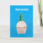 Cartão de Natal, espanhol, cupcake, árvore de<br><div class="desc">Um cartão de Natal espanhol com uma árvore de Natal decorada sobre um cupcake congelado, de uma colagem de papel pintado à mão por Judy Adamson. O cumprimento dianteiro, no texto branco em um fundo azul, é "Feliz Navidad!" e o cumprimento interno, que você pode mudar, é ". nuevo do...</div>