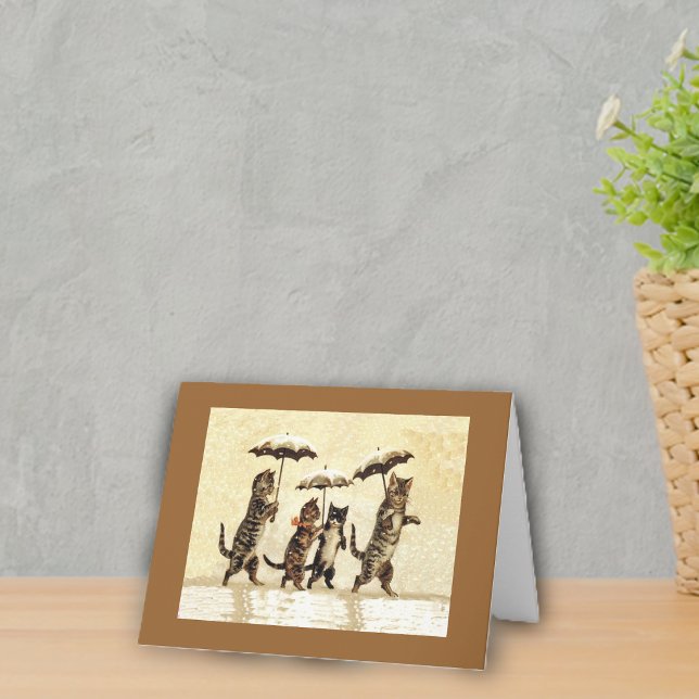 Cartão de Nota de Gatos na Neve Com Guarda-Chuvas (Four cats walking upright in snow with umbrellas on yellow with brown frame notecard.)
