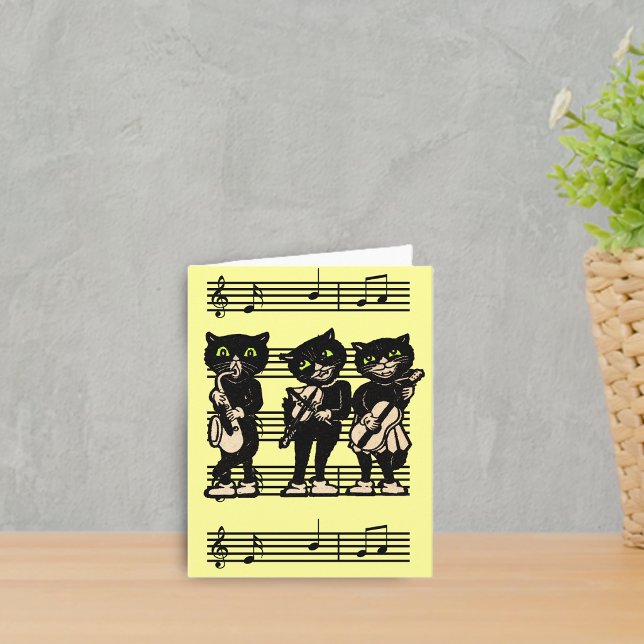 Cartão de nota musical dos gatos pretos (Three black cat musicians playing instruments on sheet of music on bright yellow notecards.)