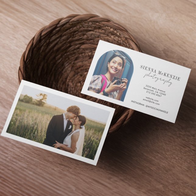Cartão De Visita Fotografia de Script de Arco Moderno Profissional (Two business cards in a woven basket on a wooden table. One card shows a smiling woman with a camera)